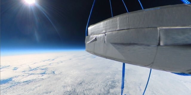 Kapsuła multimedialna misji BHR-21 na tle Ziemi i czerni kosmosu. 